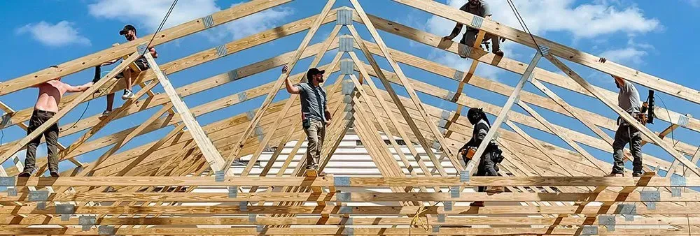 A group of construction workers are working on a wooden roof.
