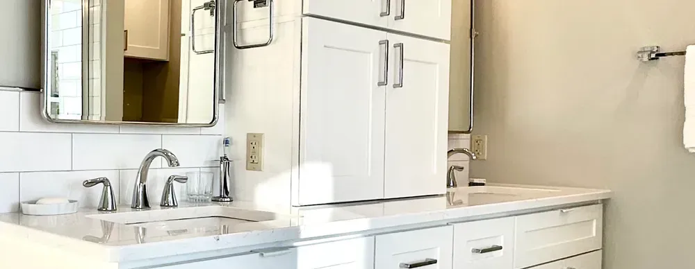 A bathroom with a sink , mirror and cabinets.
