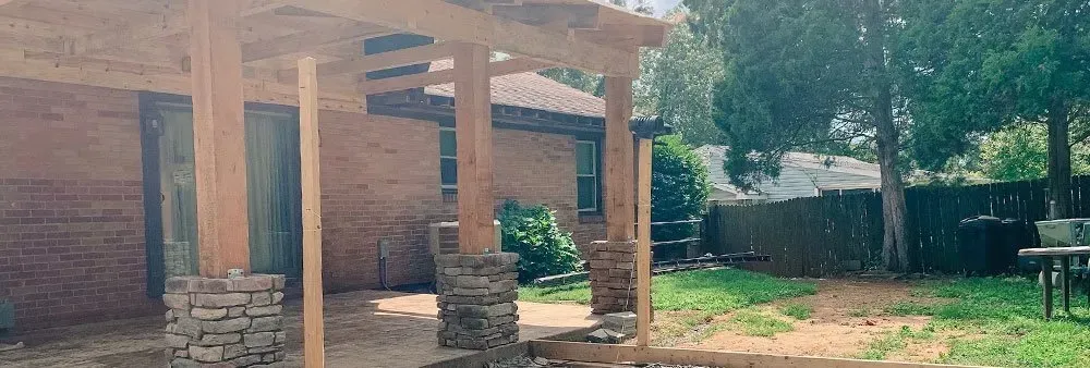 A wooden pergola is being built in the backyard of a house.
