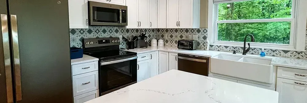 A kitchen with white cabinets , stainless steel appliances , a refrigerator , stove , microwave and sink.