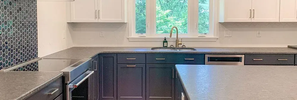 A kitchen with gray cabinets , stainless steel appliances , a sink , and a window.