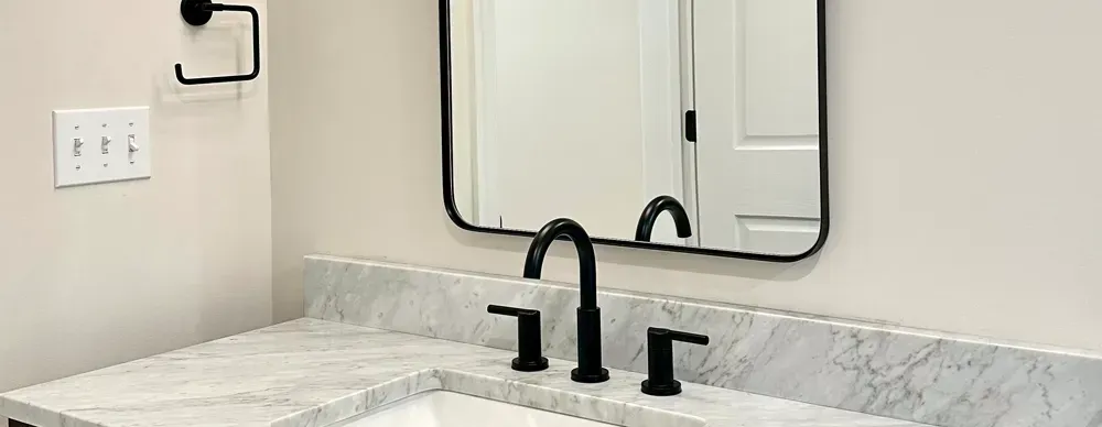A bathroom with a sink , mirror and faucet.