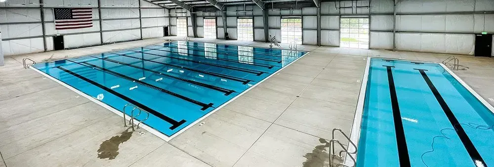 A large indoor swimming pool with an american flag on the wall.