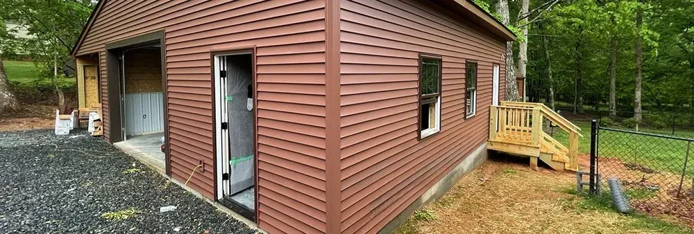 A brown garage with a wooden deck in the backyard.
