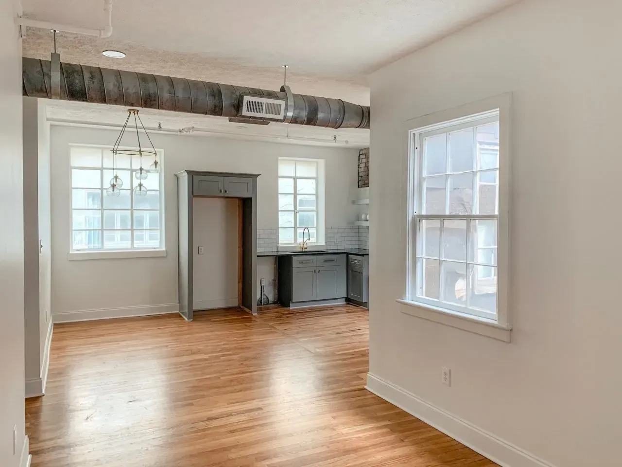 A large empty room with hardwood floors and white walls.
