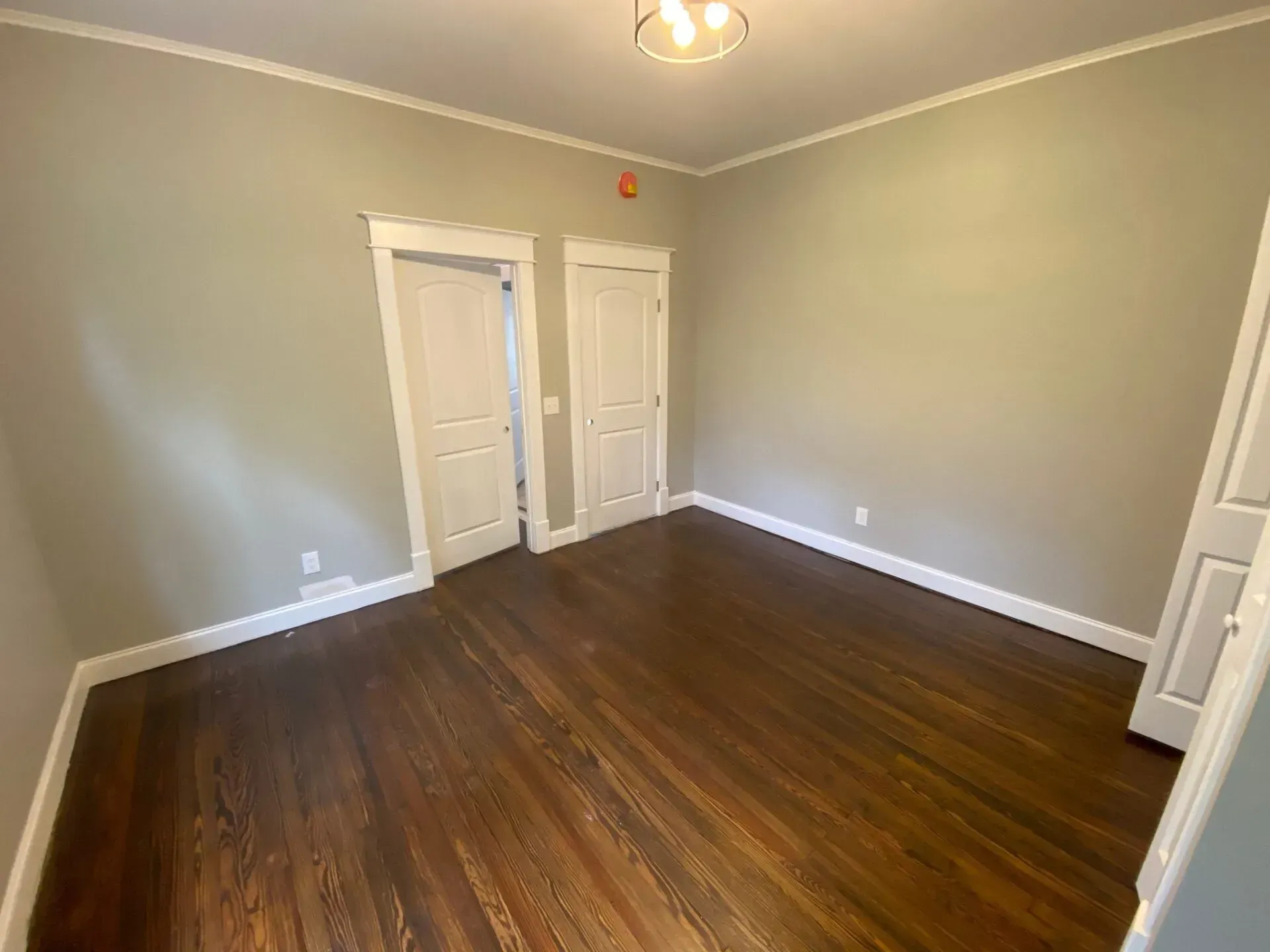 An empty room with hardwood floors and two doors.