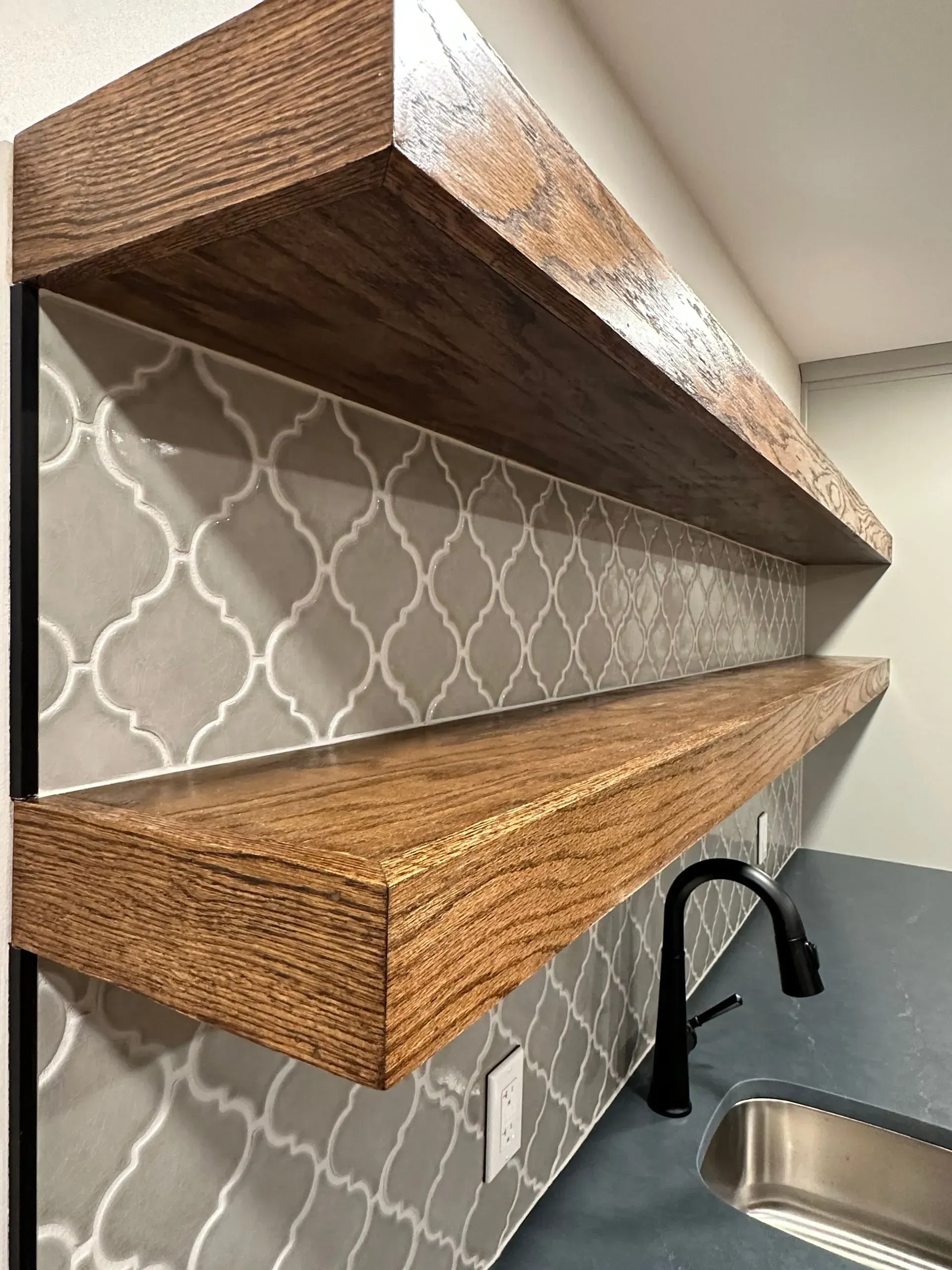 A kitchen with two wooden shelves and a sink.