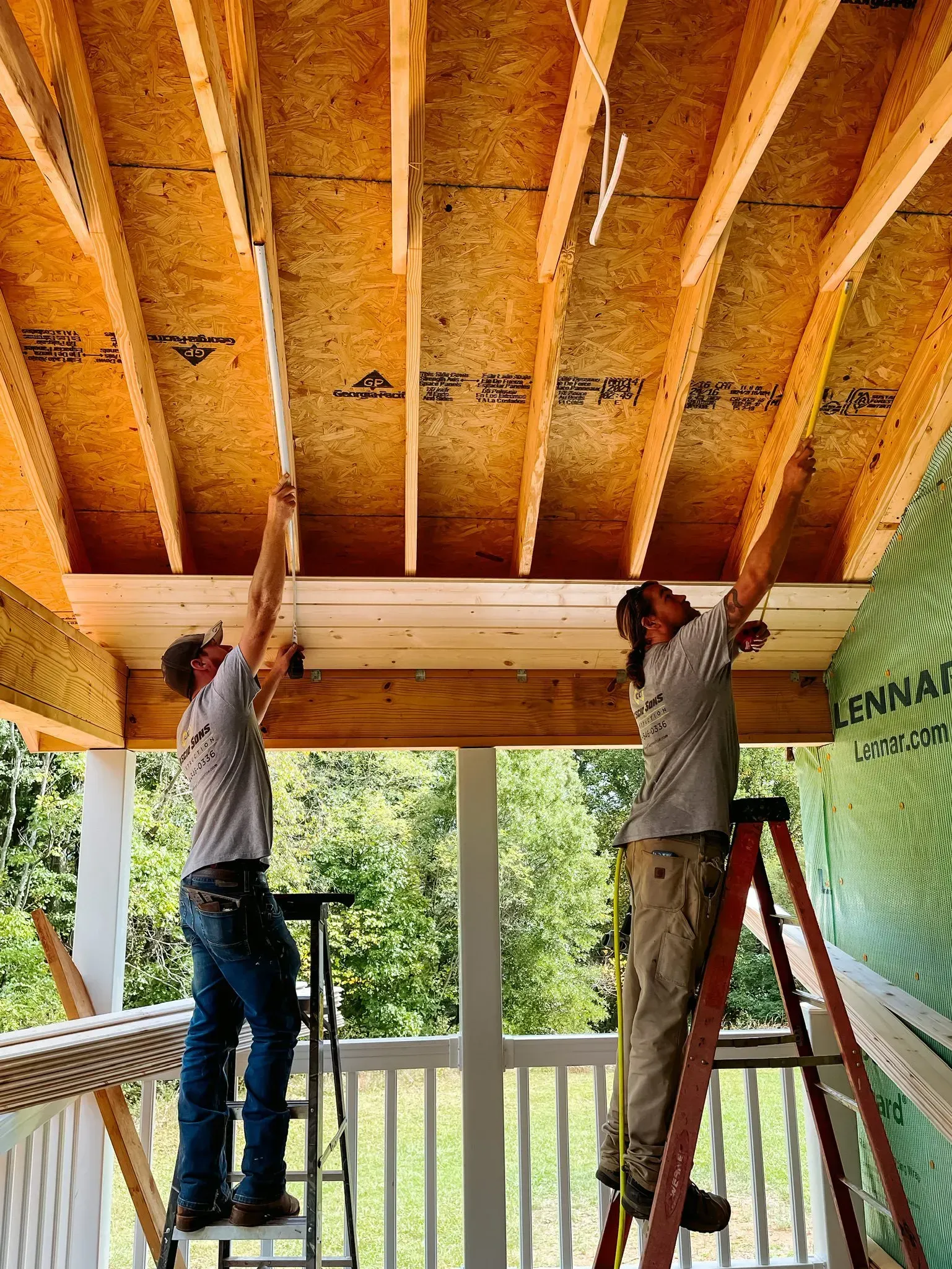 Two men are working on the ceiling of a house.