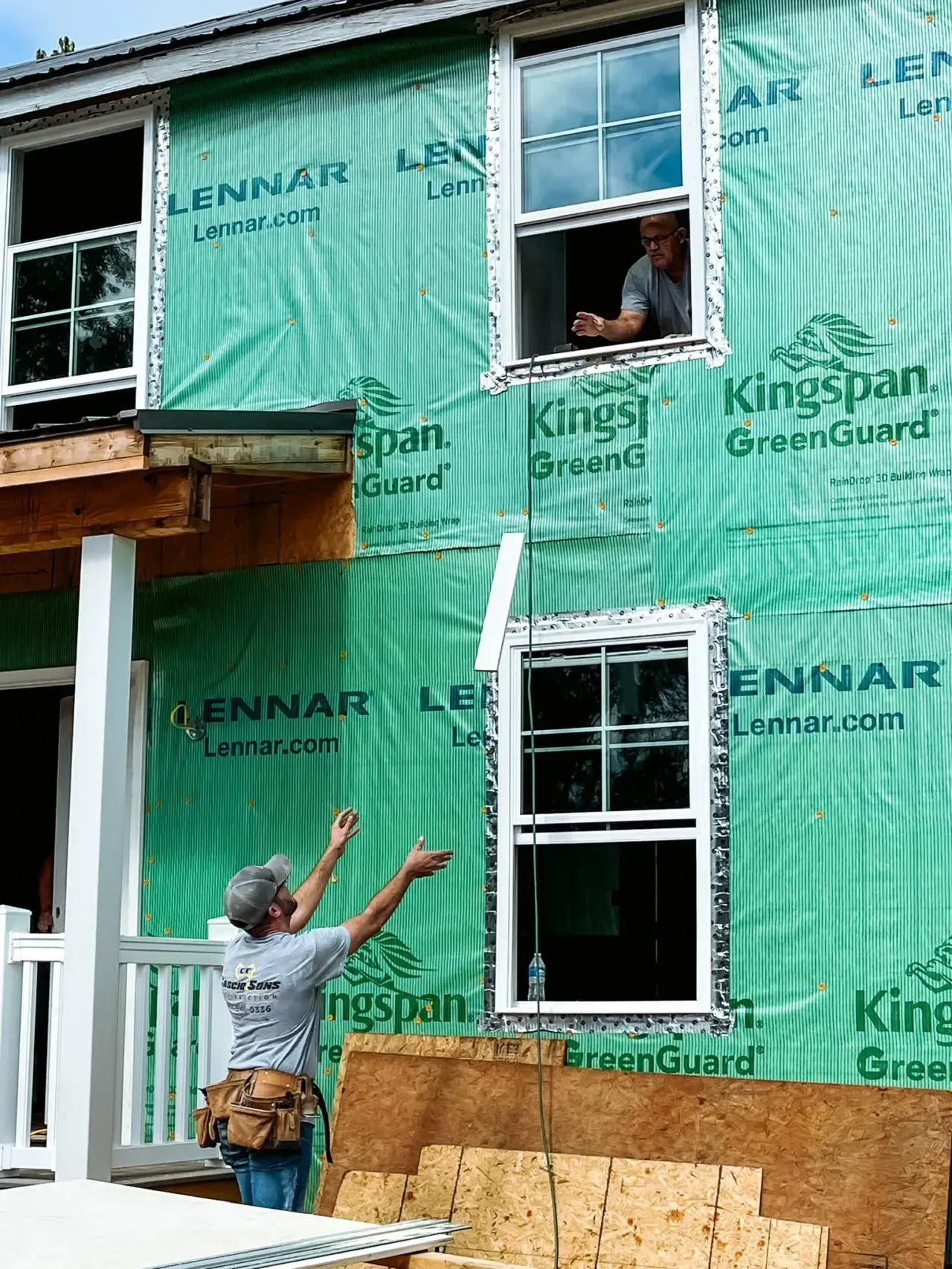 A man is pointing at a window in a house that is being built
