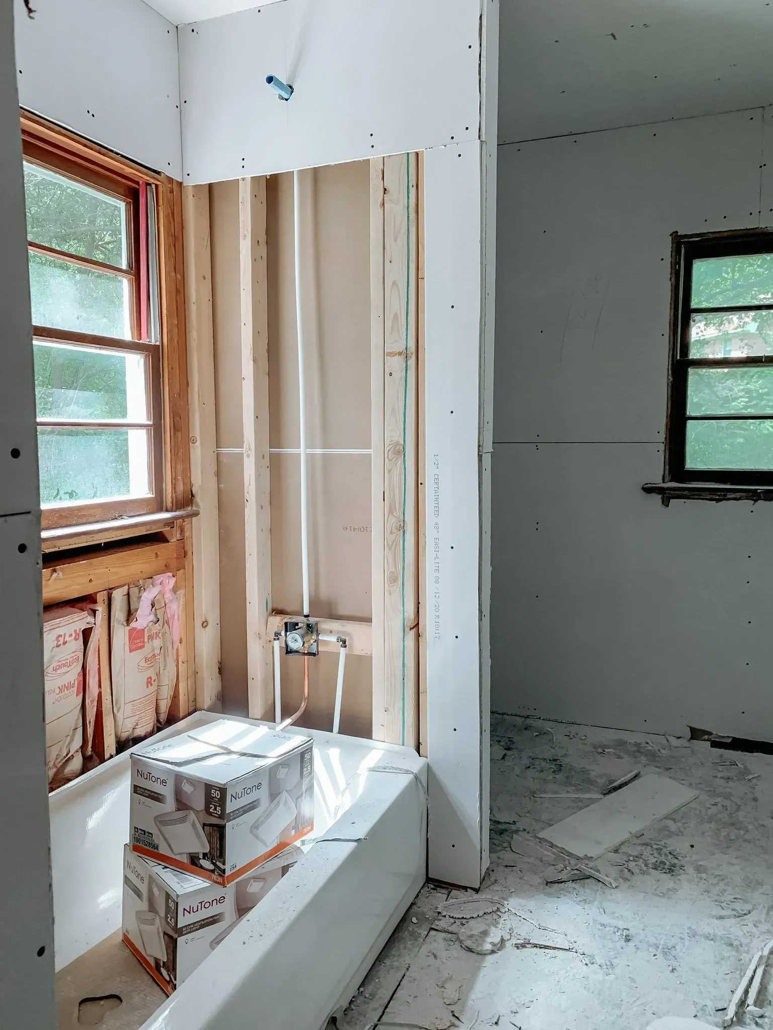 A bathroom under construction with boxes stacked on top of a bathtub.
