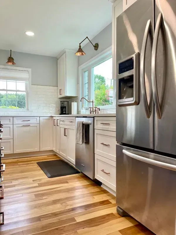 A kitchen with stainless steel appliances and wooden floors.