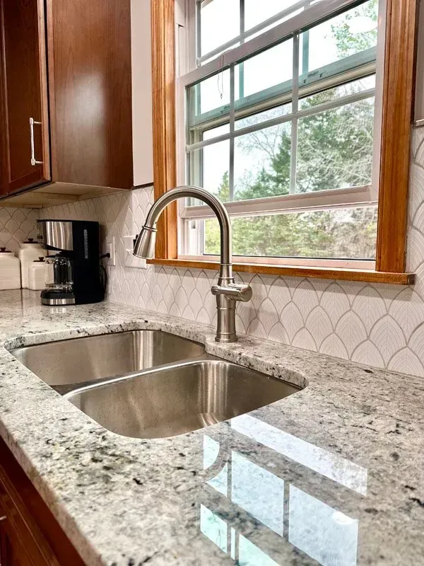 A kitchen with a stainless steel sink and a window.