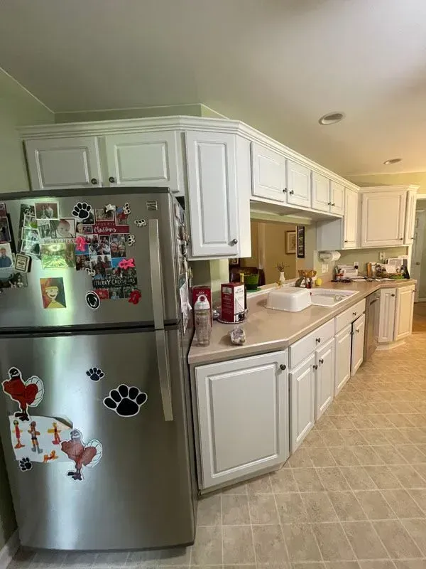 A kitchen with white cabinets and a stainless steel refrigerator.