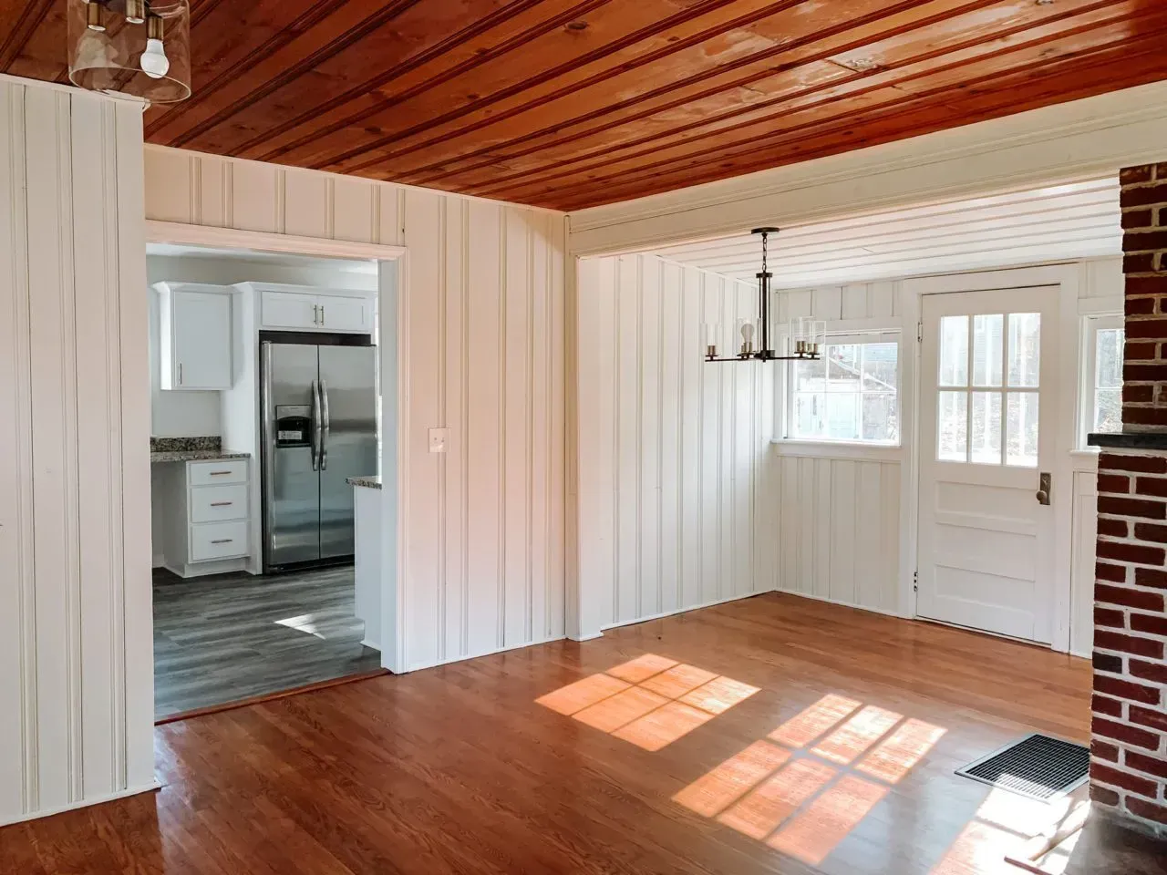 An empty room with hardwood floors and a wooden ceiling.