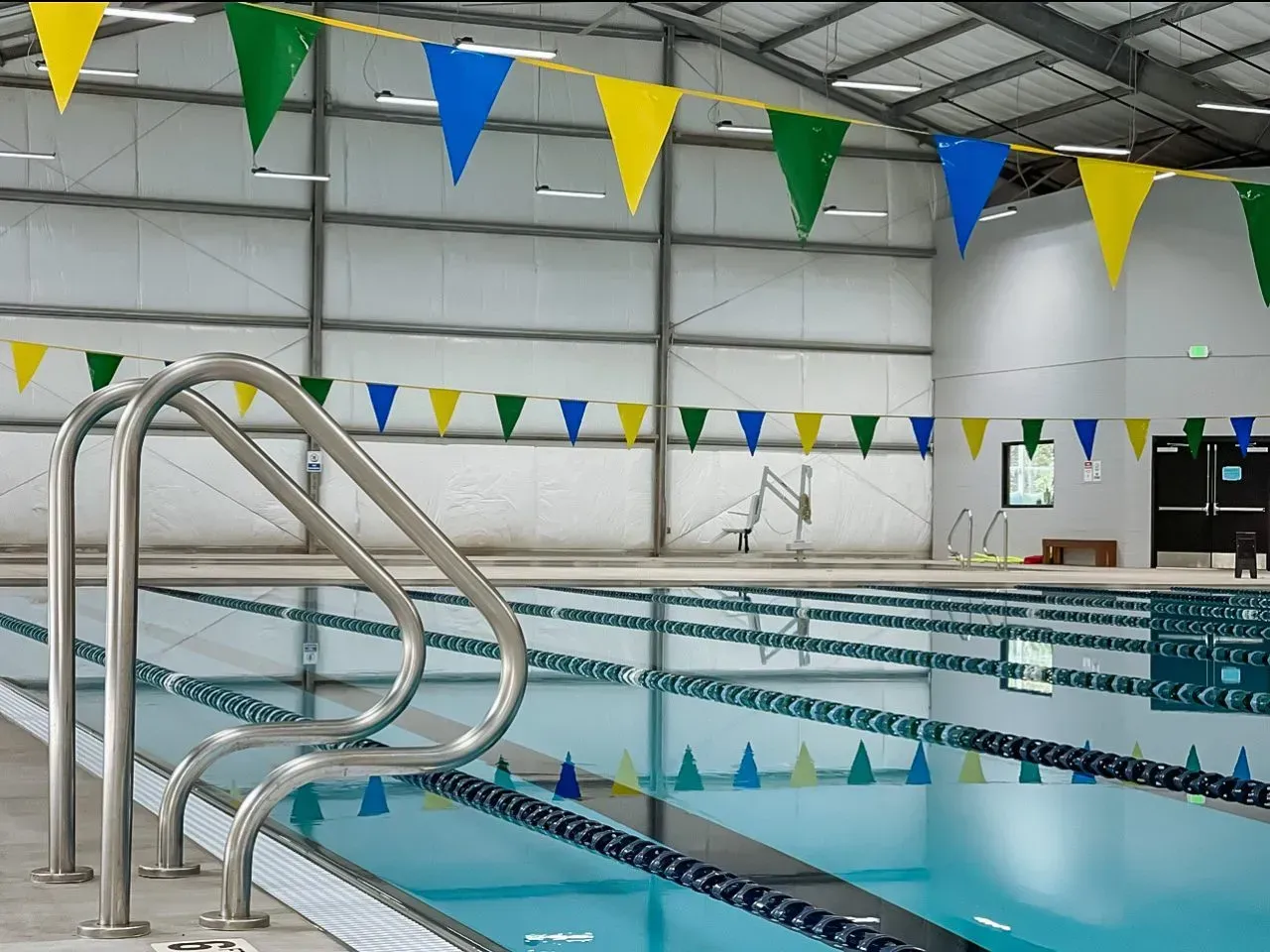 A large indoor swimming pool with flags hanging from the ceiling