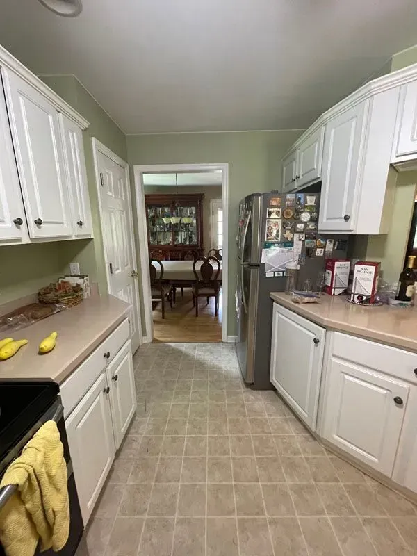 A kitchen with white cabinets , stainless steel appliances , a refrigerator and a stove.