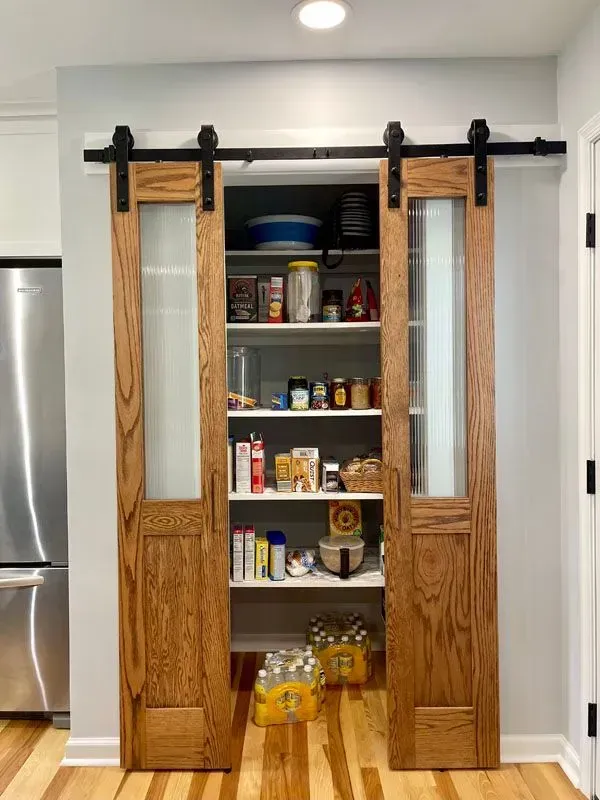A pantry with sliding barn doors in a kitchen filled with food.