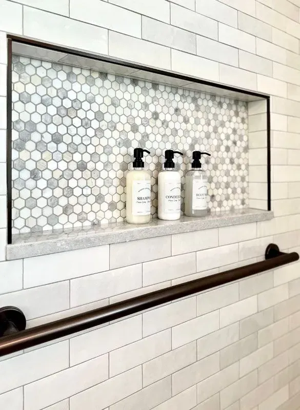 There are three bottles of lotion on the shelf in the shower.