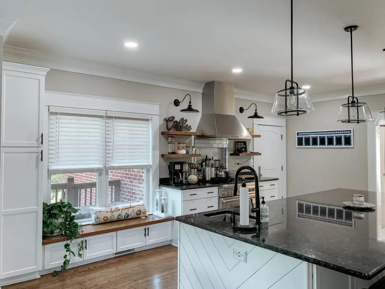 A kitchen with white cabinets , black counter tops , and a window seat.