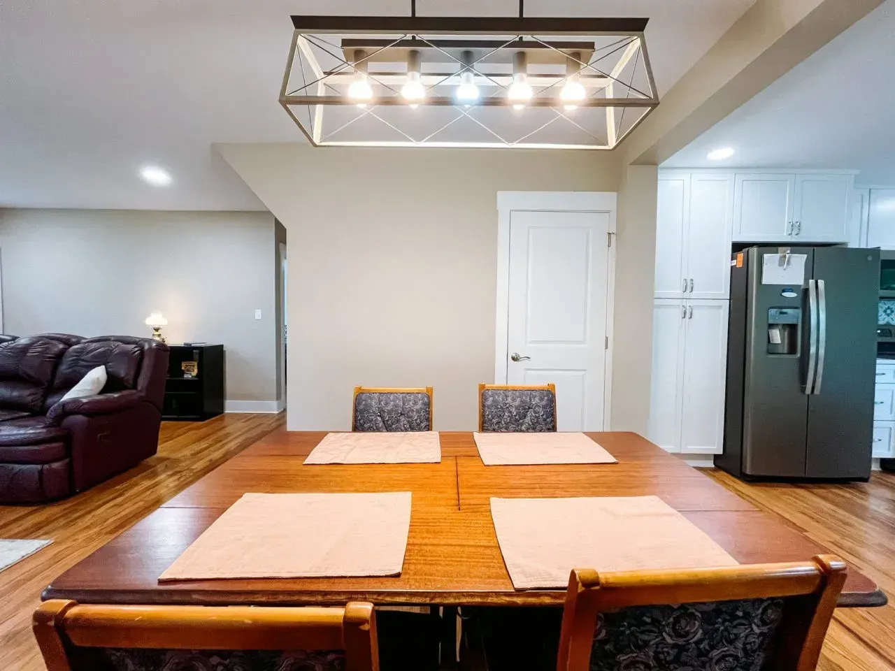 A dining room with a table and chairs and a refrigerator.