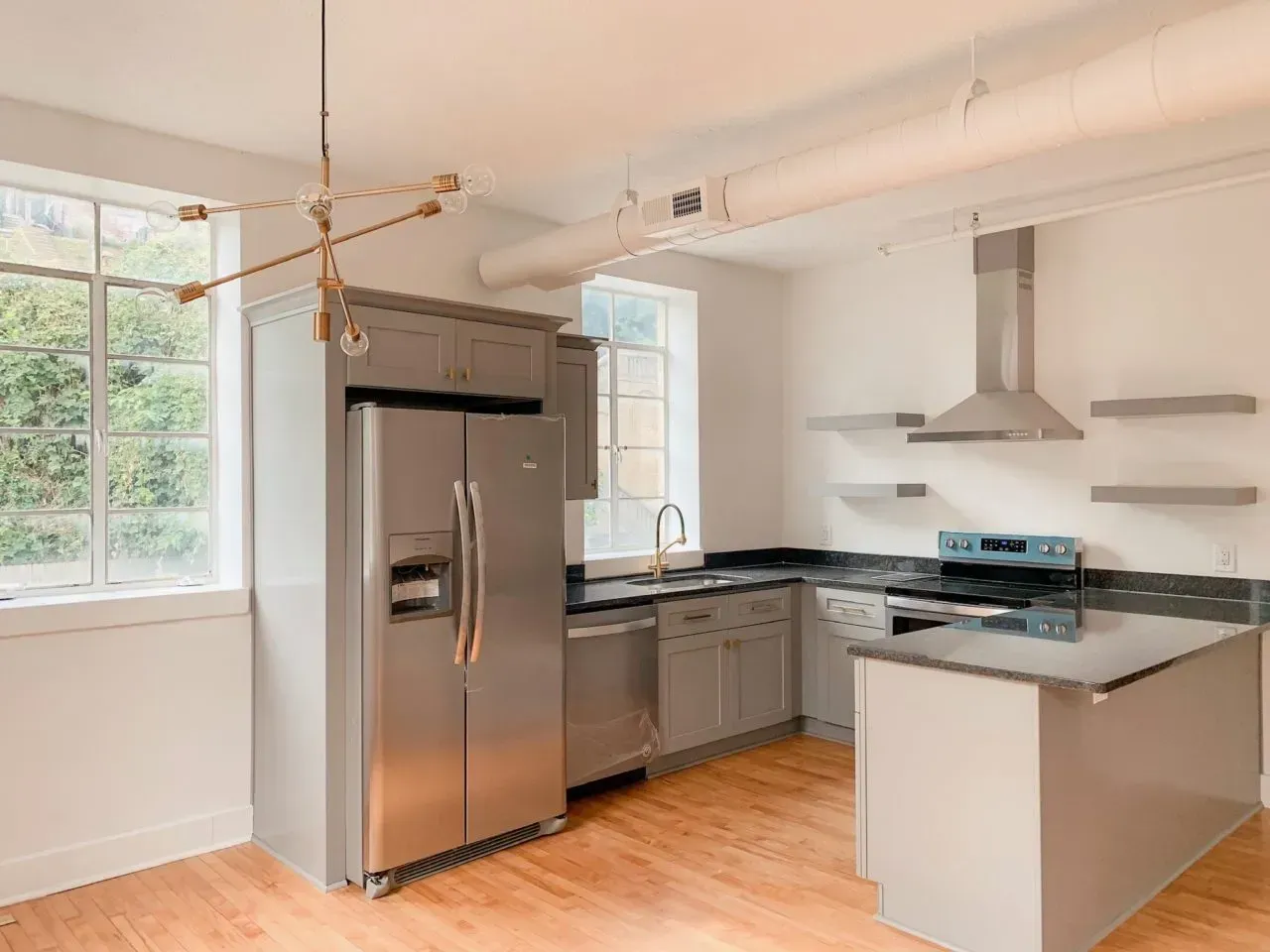 A kitchen with a stainless steel refrigerator , stove , sink , and island.