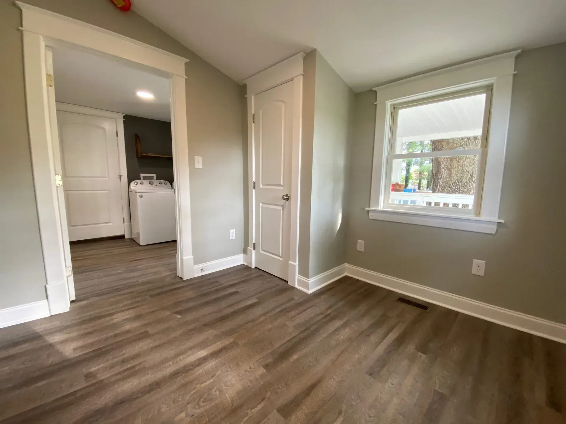 An empty room with hardwood floors and a window.