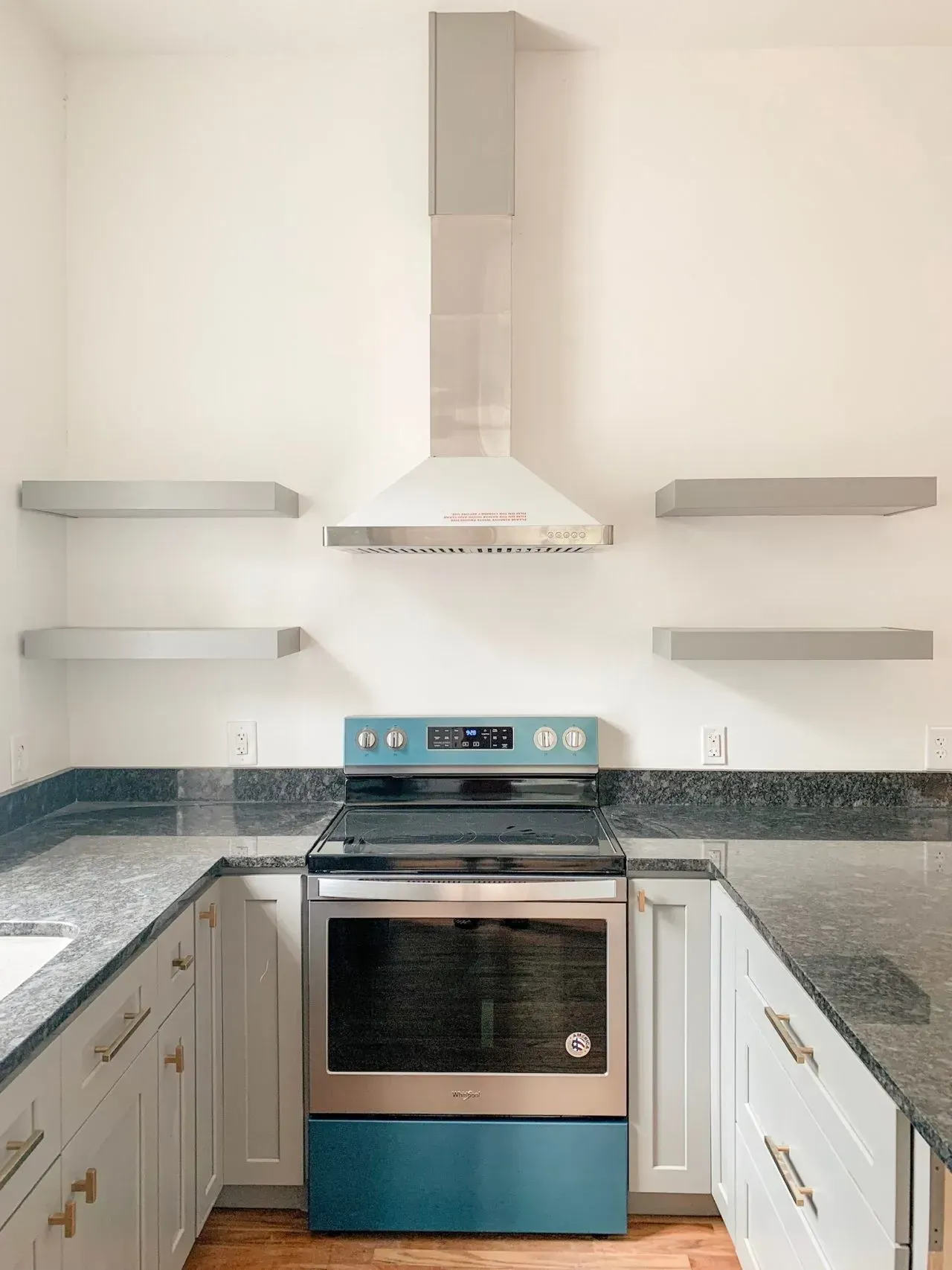A kitchen with a stove , oven , and shelves.