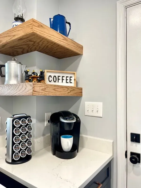 A kitchen counter with a coffee maker and a sign that says coffee on it.
