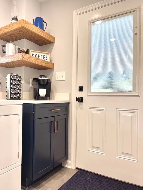 A laundry room with a washer and dryer , a coffee maker , and a door.
