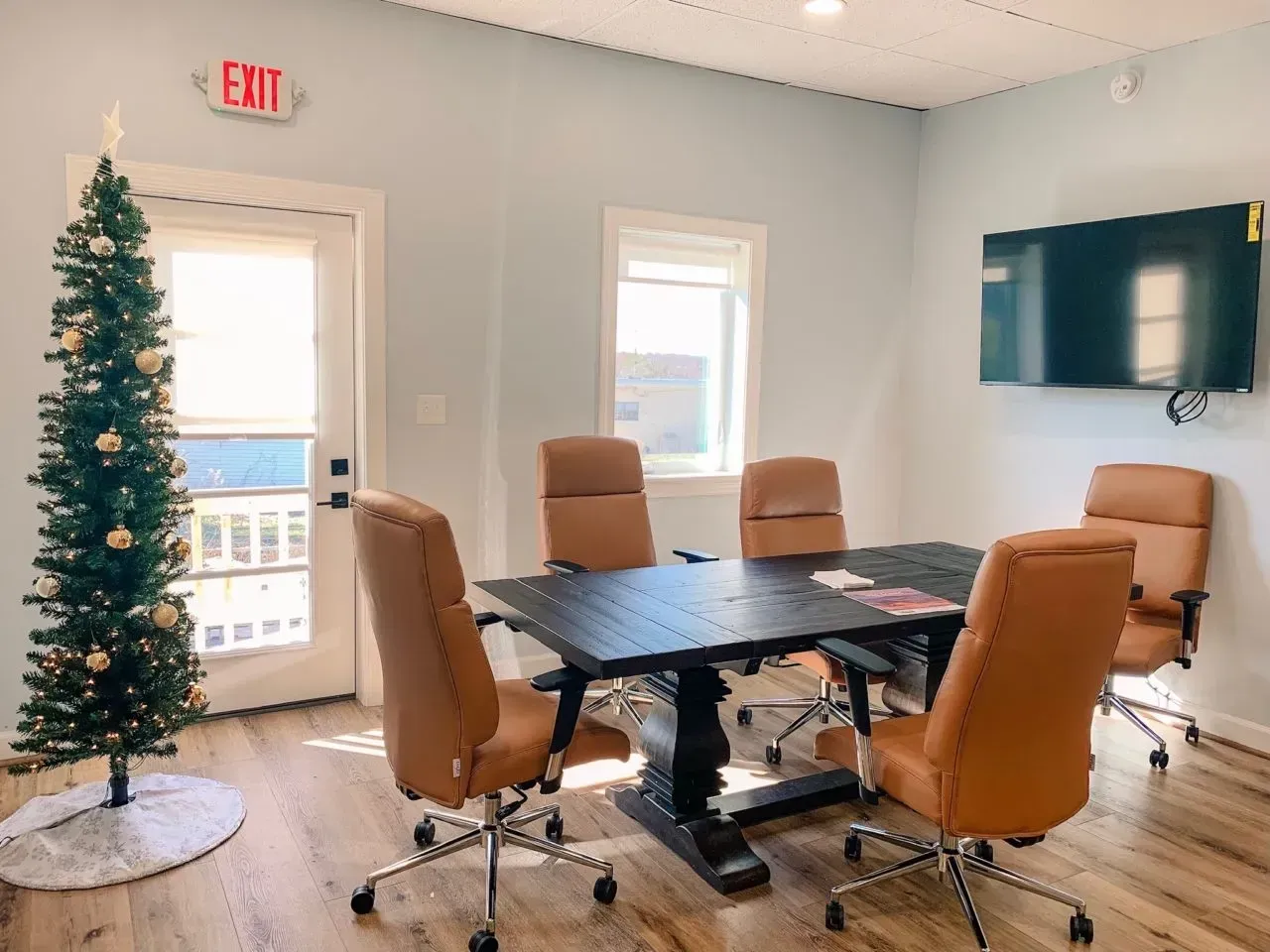 A conference room with a table and chairs and a christmas tree.