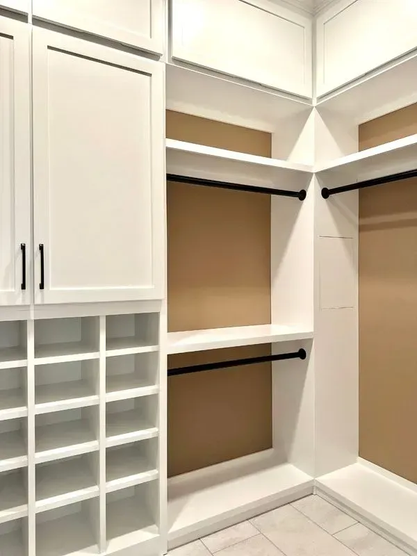 A walk in closet with white cabinets and shelves.