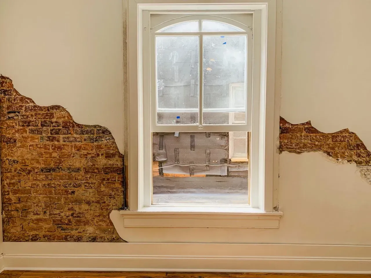 A room with a window and a brick wall.