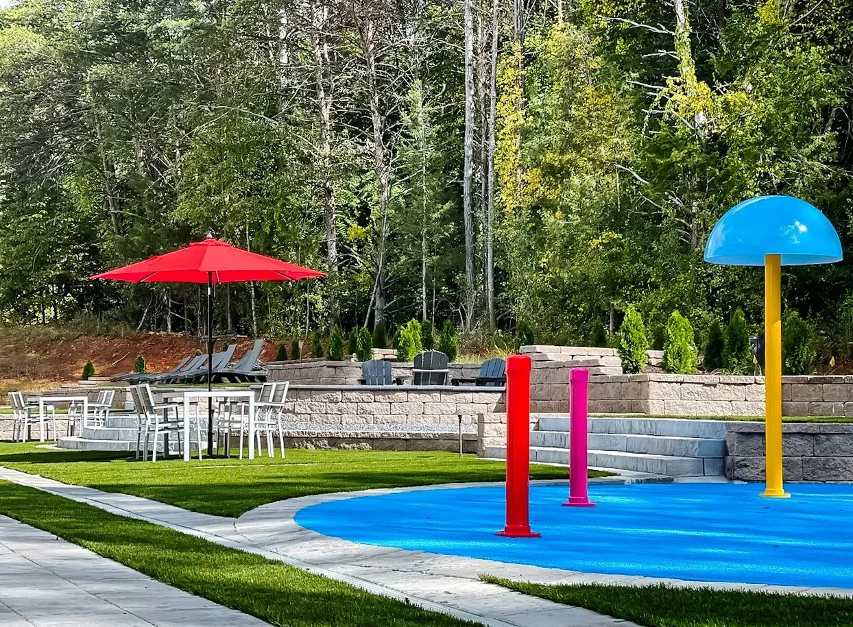 A water park with a red umbrella and a blue rubber mat.