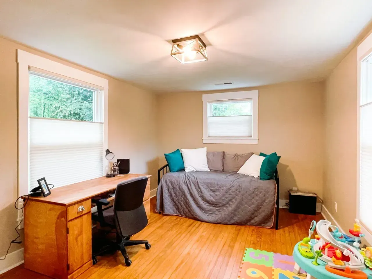A living room with a couch , desk , chair and window.