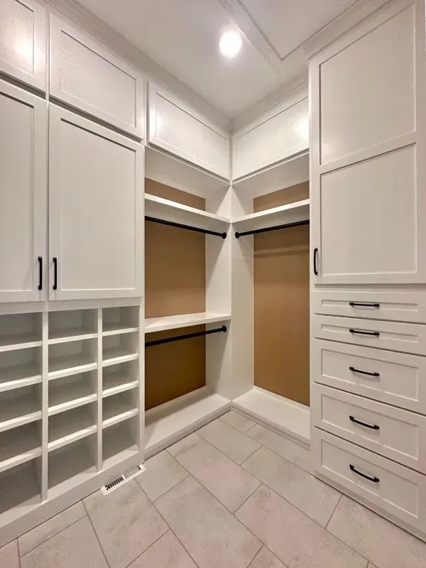 A walk in closet with lots of shelves and drawers.