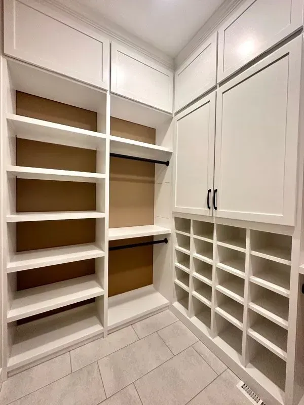 A walk in closet with lots of shelves and cabinets.