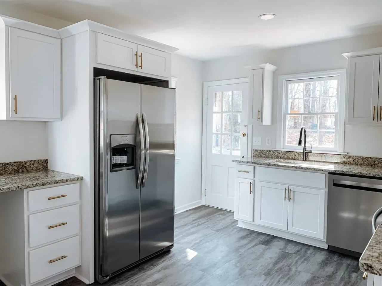 A kitchen with white cabinets and a stainless steel refrigerator.