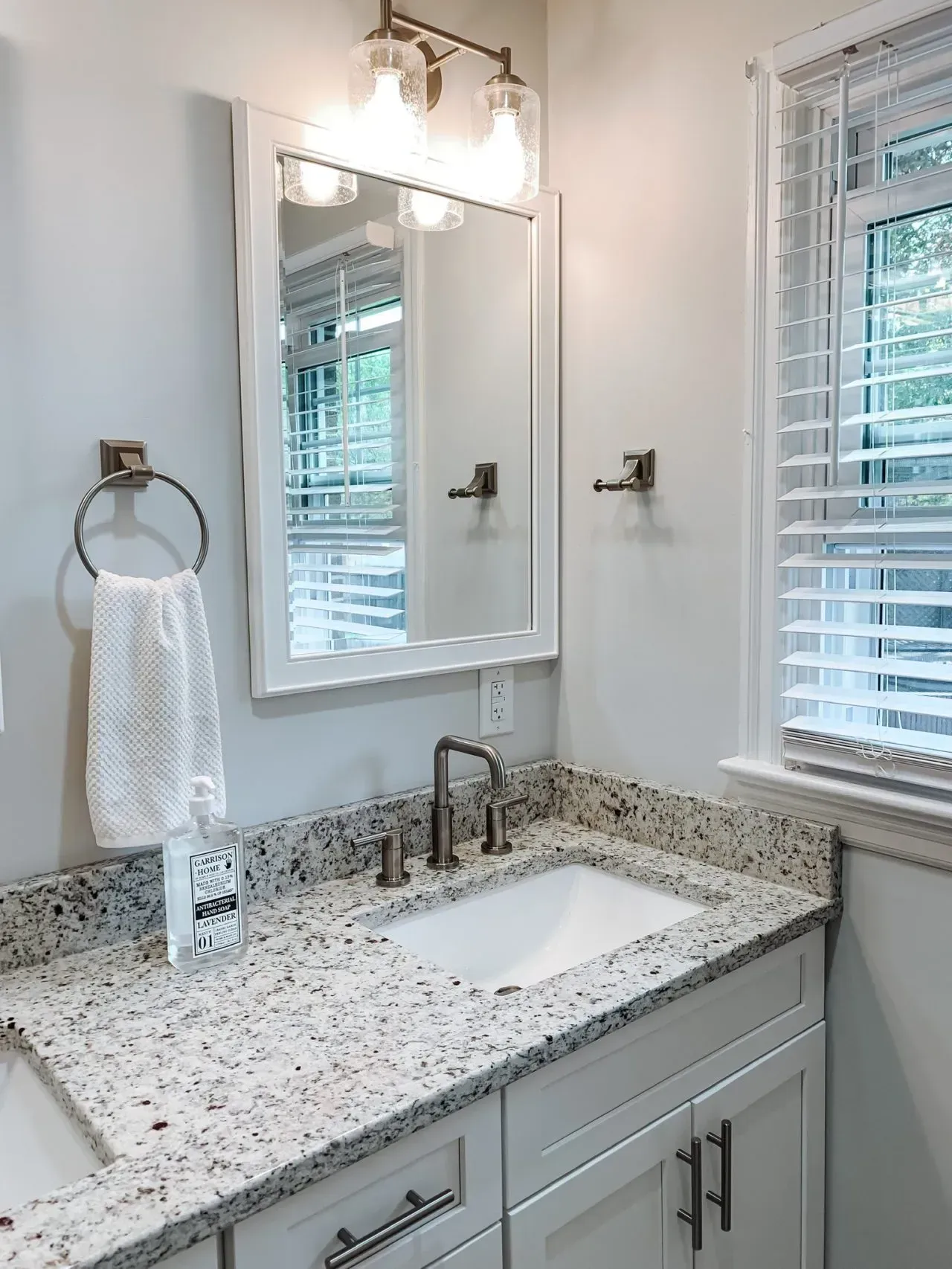 A bathroom with a sink , mirror and window.
