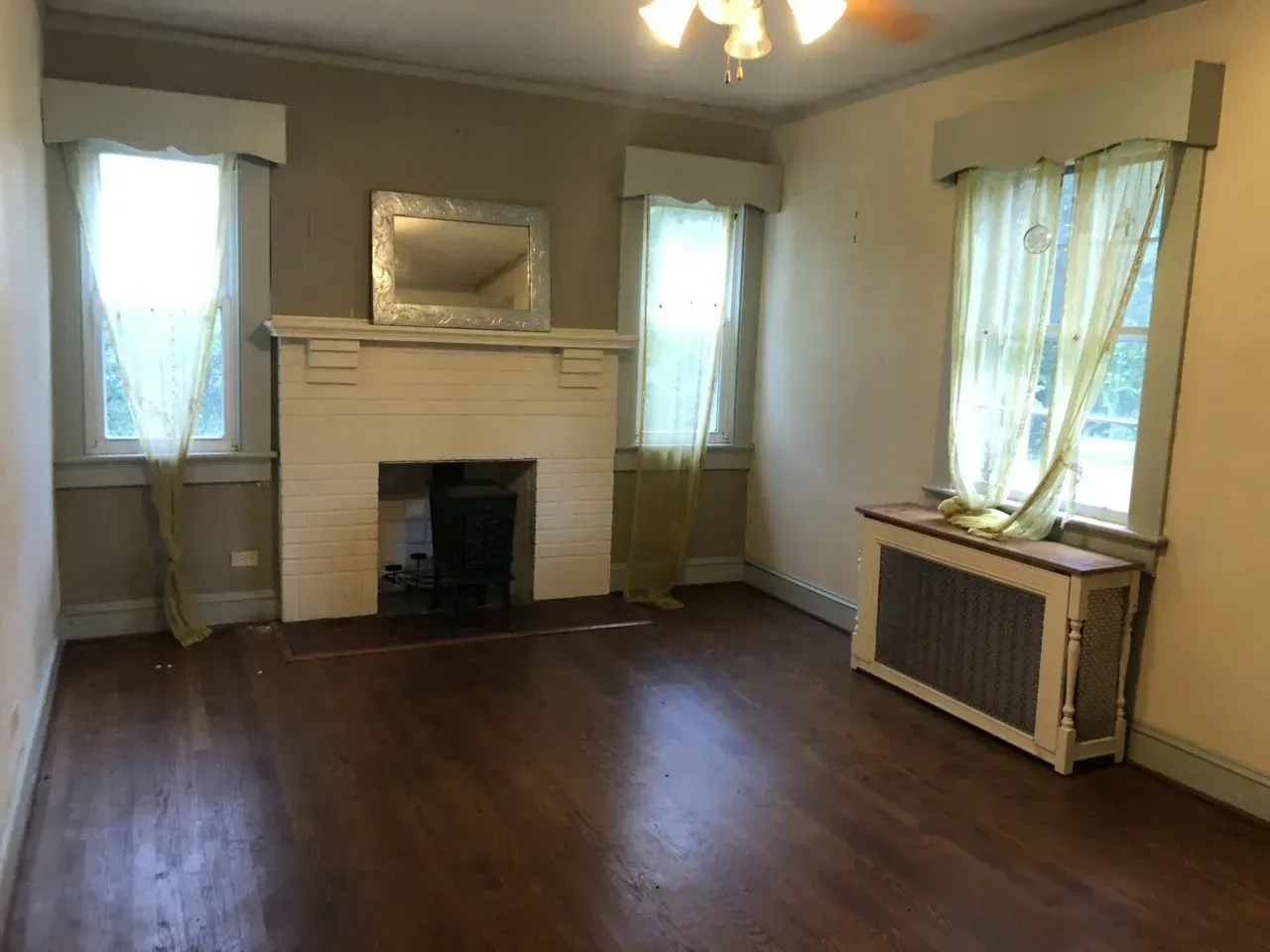 An empty living room with a fireplace and a mirror.
