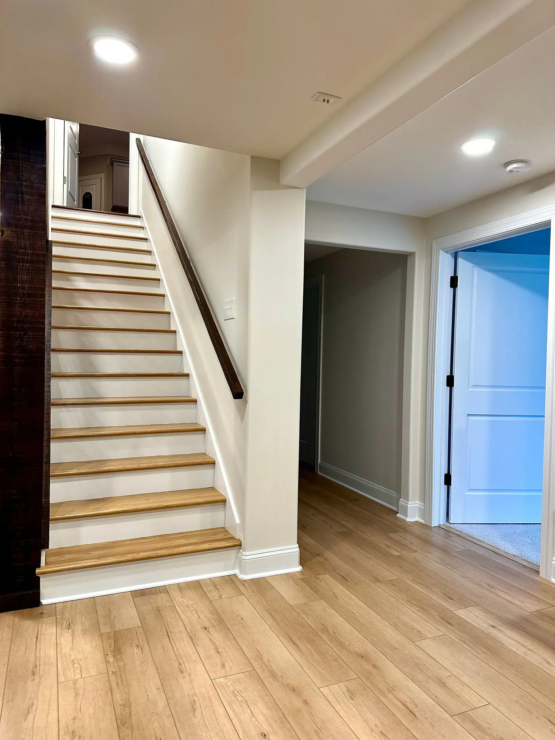 A hallway with wooden floors and stairs in a house