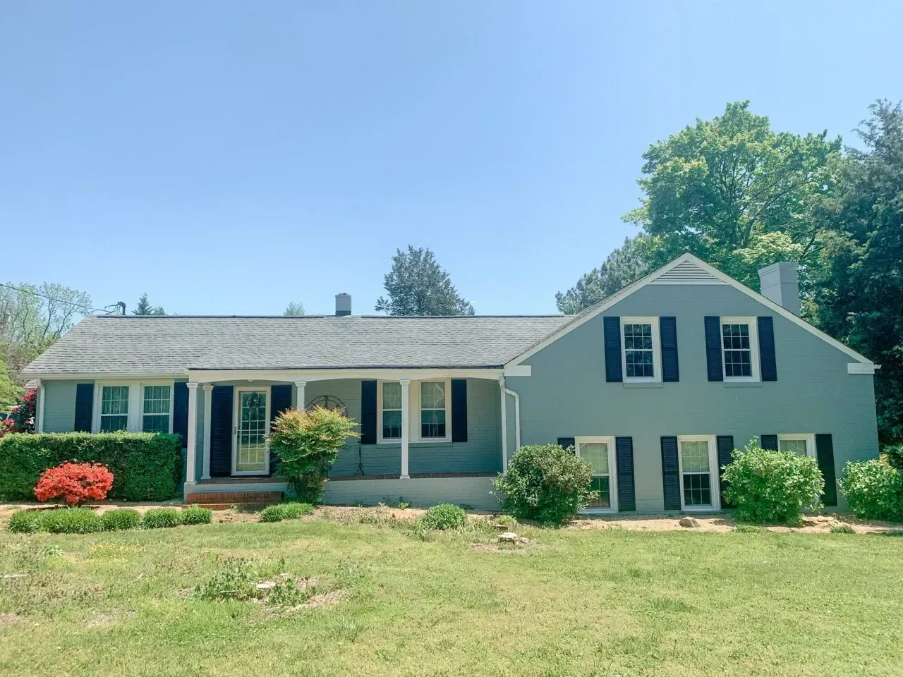 A blue house with black shutters and a porch