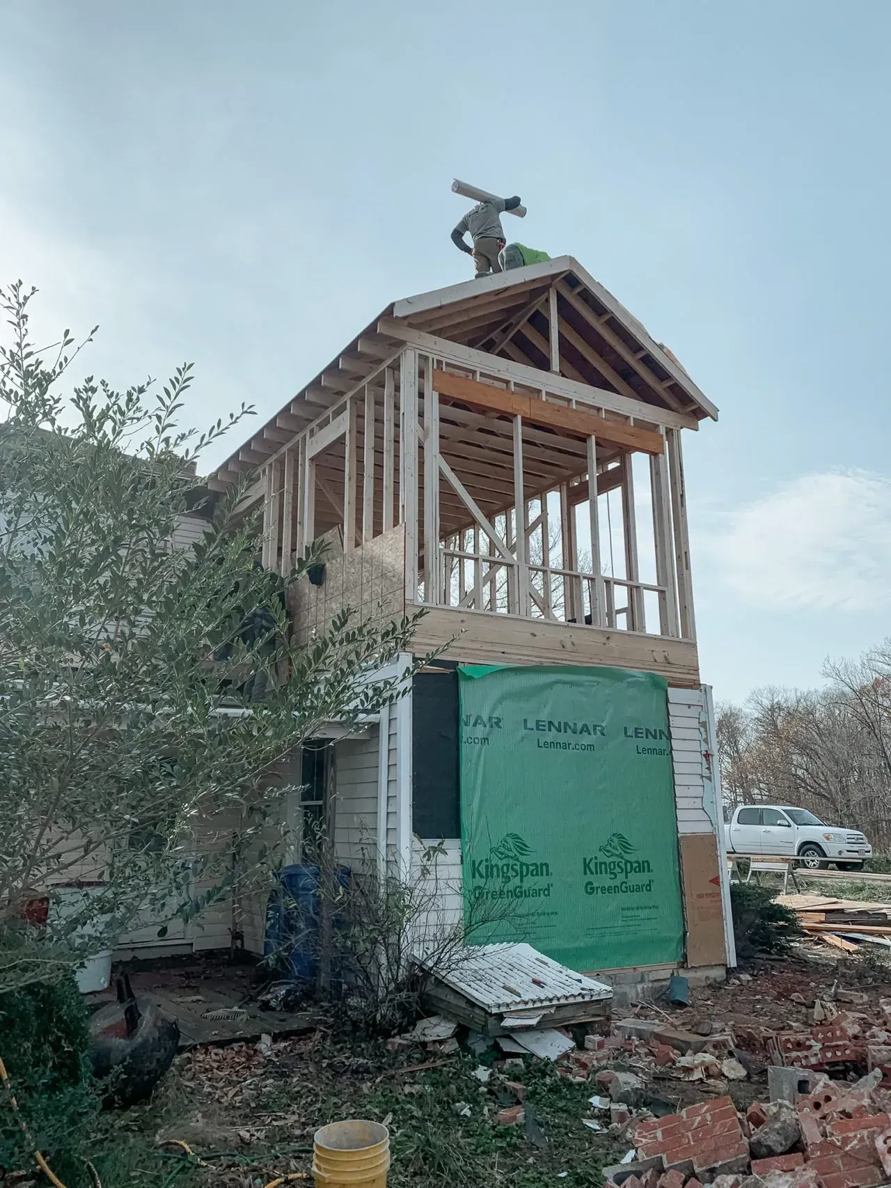 A man is standing on top of a house under construction.