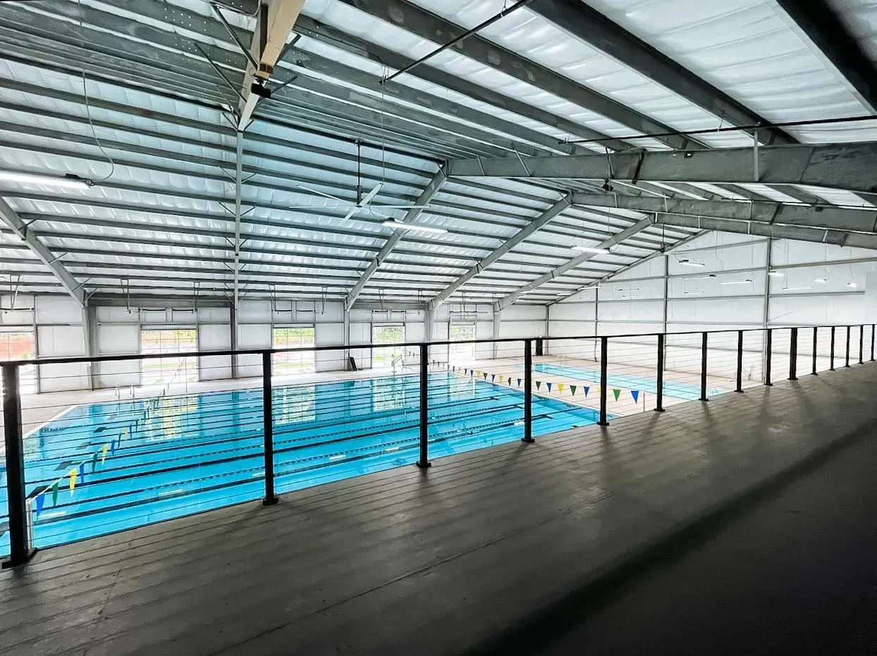 A large indoor swimming pool with a balcony overlooking it.