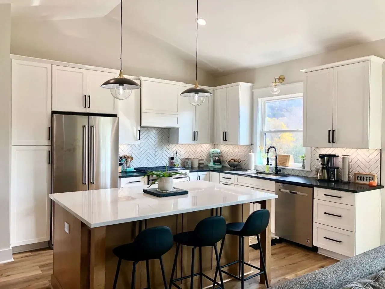A kitchen with white cabinets , stainless steel appliances , and a large island.
