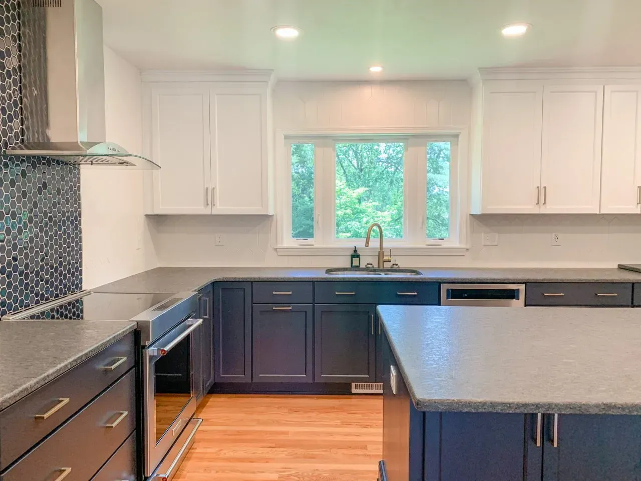 A kitchen with blue cabinets , stainless steel appliances , granite counter tops and a large island.