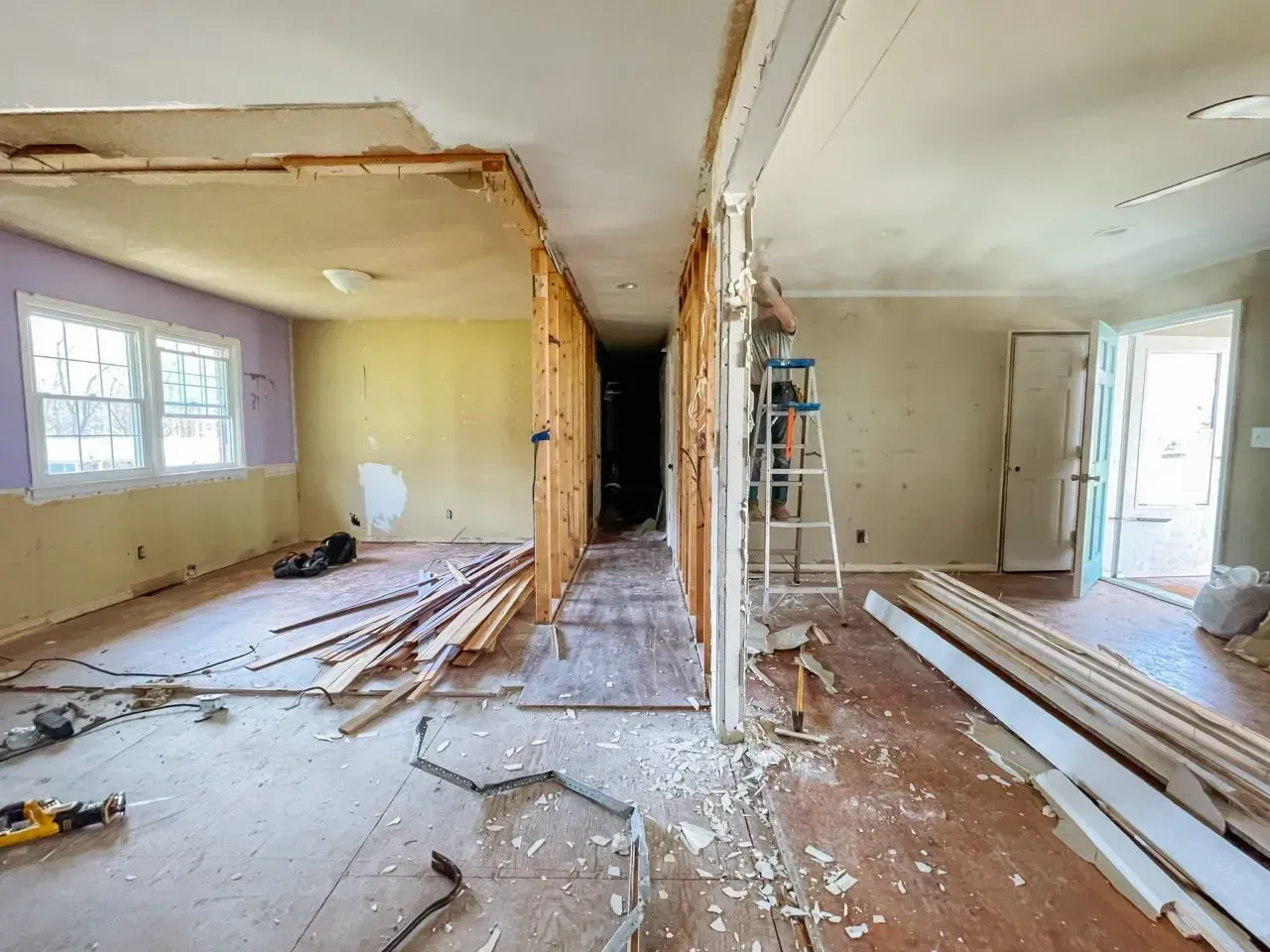The inside of a house under construction with a ladder in the middle of the room.