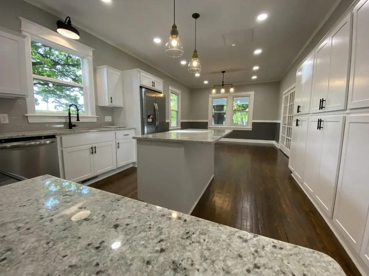 A kitchen with white cabinets , granite counter tops and stainless steel appliances.