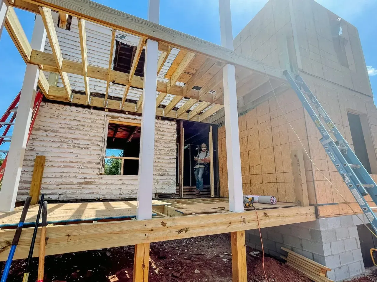 A house is being built with a wooden deck and a ladder.
