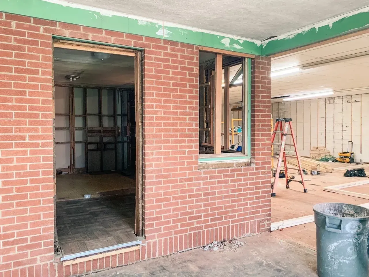 A brick wall with a window in it is being remodeled.