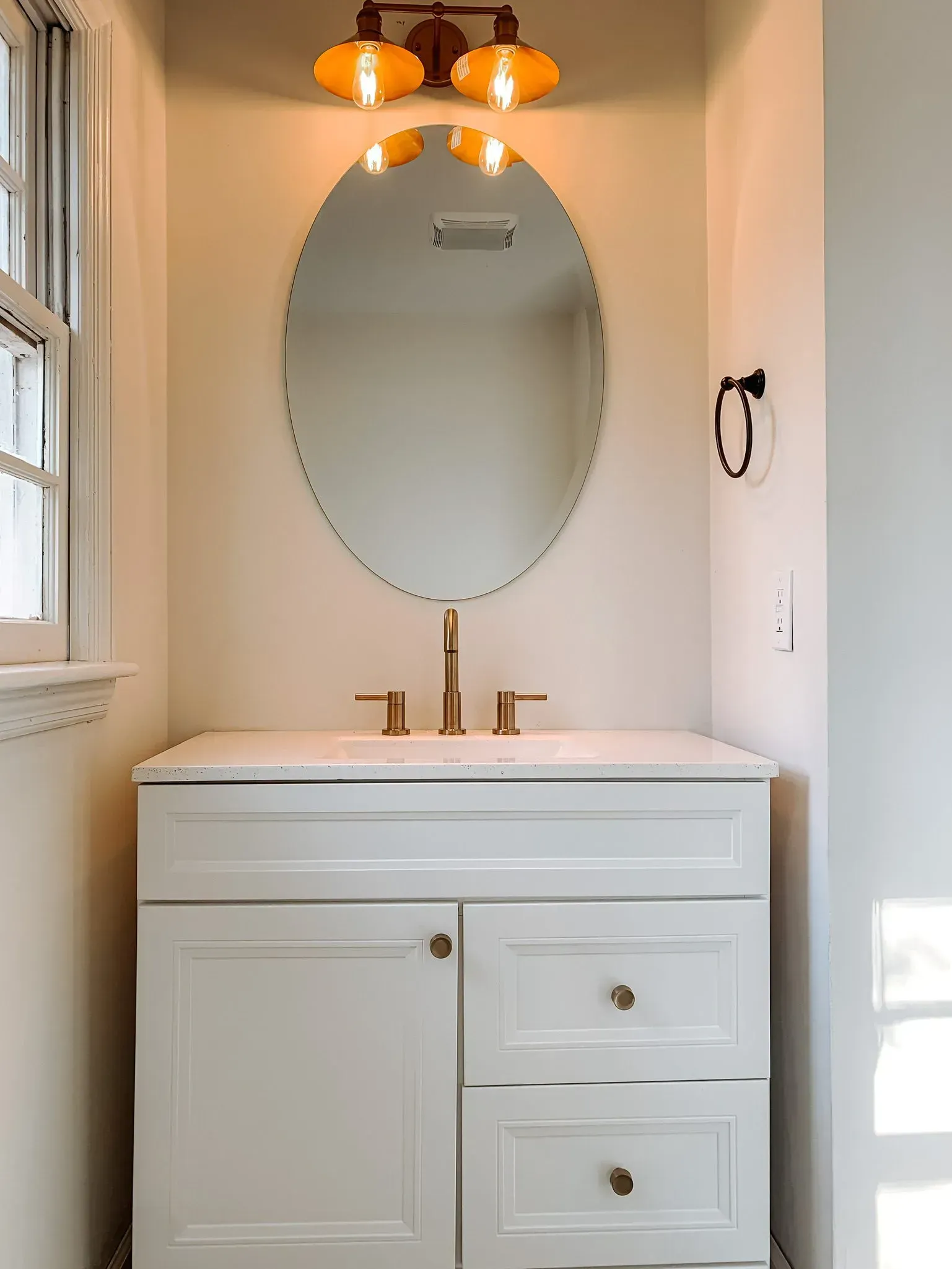 A bathroom with a sink , mirror and light fixture.